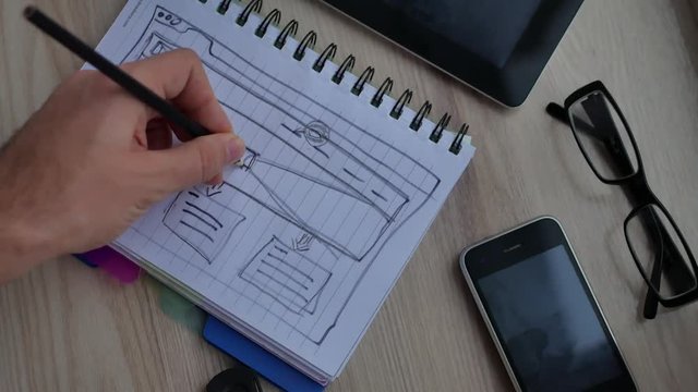 Web designer draws the layout of the site in his book.