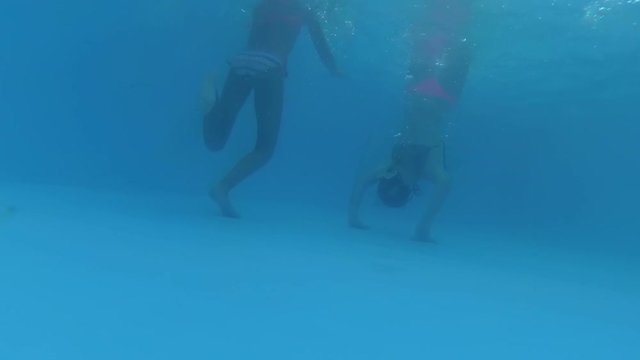 two teenage girls and a boy spend fun underwater in a swimming pool, have fun