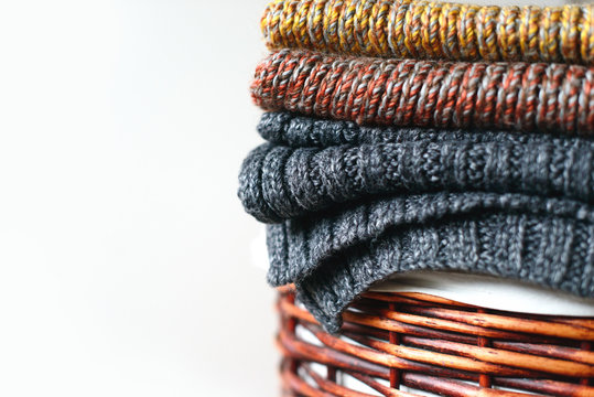 Pile of knitted winter scarfs on straw basket isolated on white background. Free copy space.