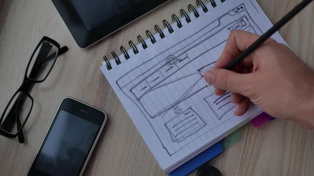 Web designer draws the layout of the site in his book.