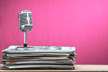 Retro microphone with newspaper on wooden table - announcement concept