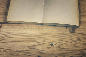 Detail of open vintage book on wooden table.  Retro toned image.