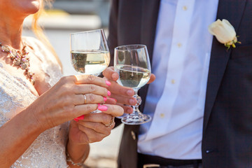 Wedding selebration. Bride and groom holding glasses of champagne making a toast, hands with glasses close up