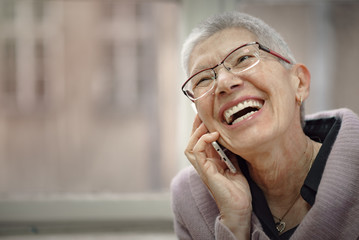 Smiling senior elderly lady having a pleasant conversation over her cell phone