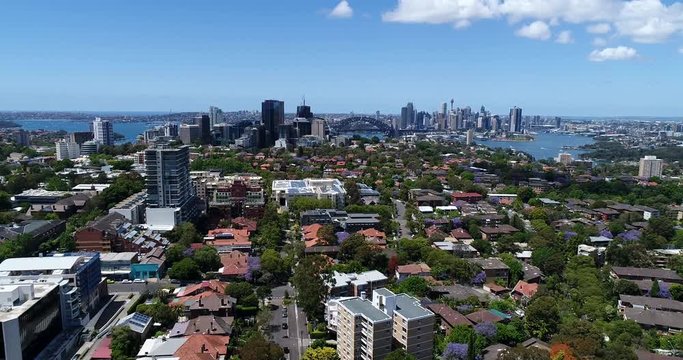Lower North Shore residential suburbs with small houses and green streets towards Sydney Harbour and city CBD landmarks and high-rise towers.
