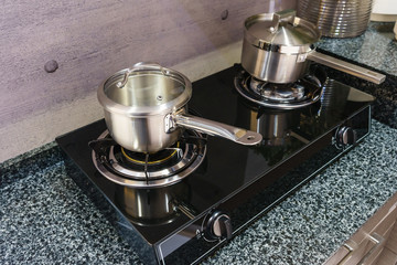 Close-up of stainless steel cooking pot on induction hob in contemporary modern home kitchen.