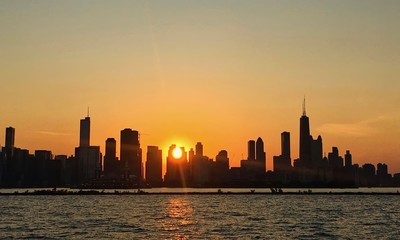 Fototapeta na wymiar Sunset over Chicago skyline with ball of sunlight peeking through buildings