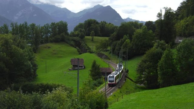 View of a train in green hills Thun Brienz in Swiss alps region of Interlaken in Switzerland