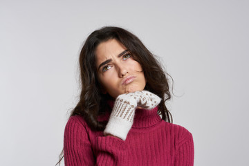 brunette woman frowns and looks up, hand near chin, light background, new year