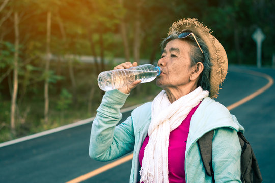 Grandma drinking water during the trip, Concept backpack travel.