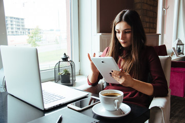 Young attractive woman sitting in a cafe in the morning before her work and planning tasks for the whole day. Beautiful lady talking on the phone and discussing business strategies with her colleague.