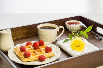 Fresh belgian waffle with berries with coffee breakfast on a tray.