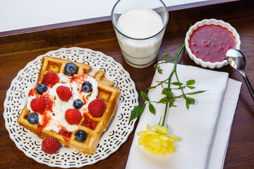 Fresh belgian waffle with berries with milk breakfast on a tray.