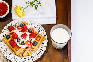 Fresh belgian waffle with berries with milk breakfast on a tray.