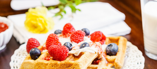 Fresh belgian waffle with berries with milk breakfast on a tray.