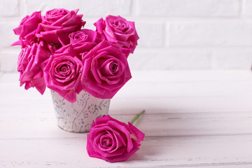 Bright pink roses flowers in pot  on white  wooden background.