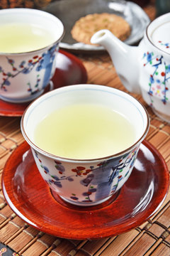 Japanese green tea and teapot on bamboo mat
