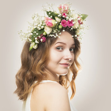 Beautiful young woman in a floral wreath of roses