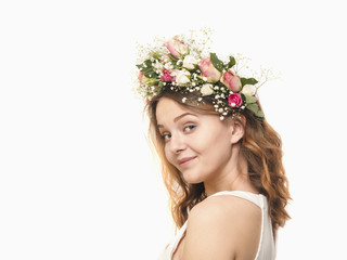 Beautiful young woman in a floral wreath of roses