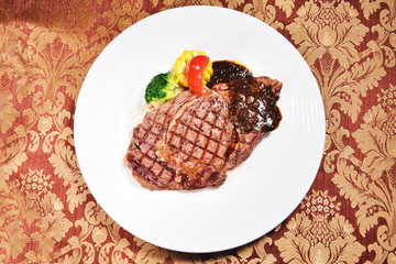 Rib eye steak with vegetables on white plate