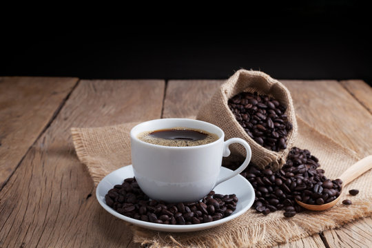 coffee cup and coffee beans on old wood plank background.