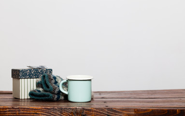 vintage bright green cup with hot tea and warm gloves on wooden table