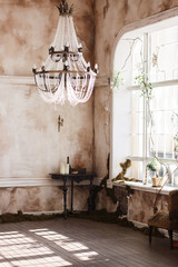 Old fashioned vintage room corner with black table and candles. Dirty walls covered with fern, big crystal ceiling light