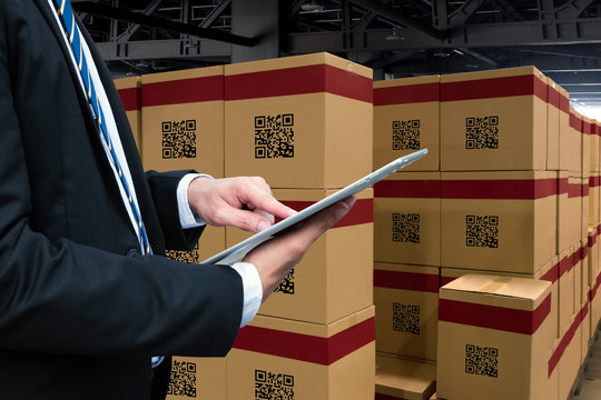 Smart logistic industry 4.0 , QR Codes Asset warehouse and inventory management supply chain technology concept. Businessman using tablet and group of boxes in storehouse can check product inside.