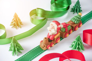 Santa claus driving train on ribbon with pulling christmas trees and gift box