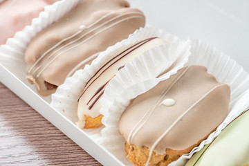 french eclairs in box on wooden table closeup