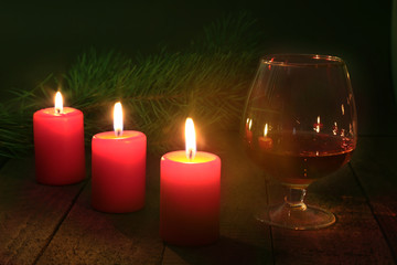 christmas decoration. glass of cognac or whiskey, christmas candles and gift box on a wooden background.