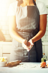 Female hands kneading dough, baking background. Cooking ingredients - eggs, flour, sugar, butter, milk, rolling pin on white style kitchen. Copy space