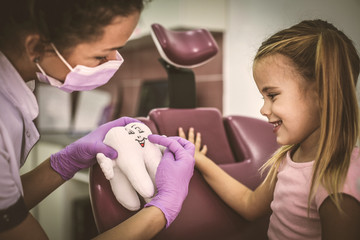 Dentist learning little girl about teeth .