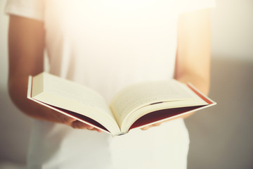 Young girl in white T-shirt reading opened book. Copy space. lifestyle and school concept