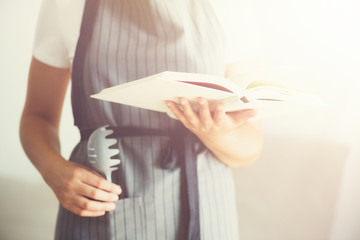 Girl wearing grey apron and reading book. Lifestyle concept