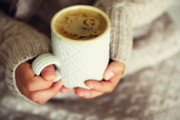 Famale hands holding a cozy ceramic handmade mug with coffe. Winter and Christmas home time concept. Lifestyle. Copy space