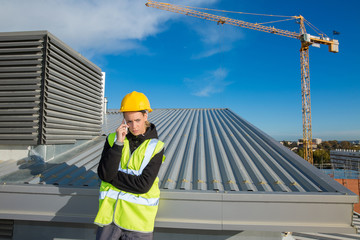 female ingineer with hardhat using electronics on construction roof