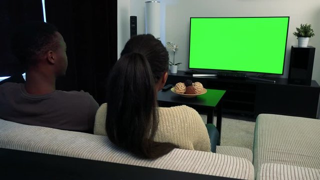 Young black couple watch television in living room - green screen 