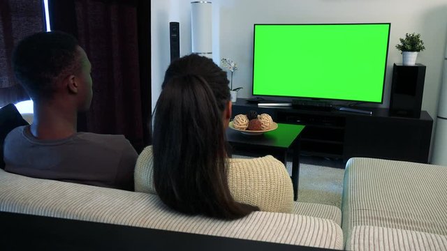 Young black couple watch television in living room - green screen 