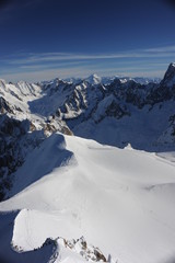 Panorama of French Alps with mountain ranges covered in snow and blue sky in winter