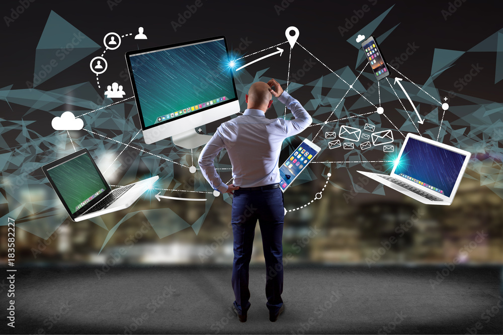 Poster businessman in front of a wall with computer and devices displayed on a futuristic interface with in