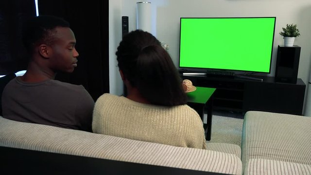 Young black unhappy couple watch television in living room and they argue 