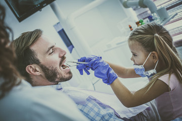Fototapeta premium Smiling little girl playing with her father at dentist office.