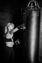 Woman hits the heavy bag with a strong kick. Concept about fit boxe, martial arts and sport. Simple...