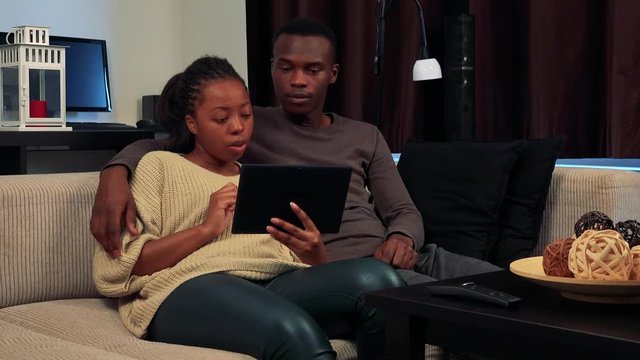 Young black couple work together on tablet in living room