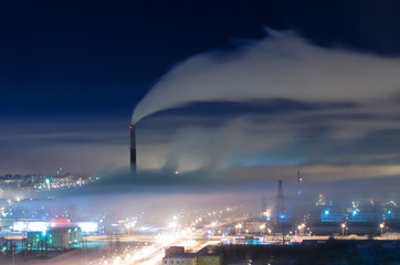 Industrial district of the city, pipes and smoke, with fog and smog at night.