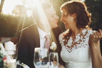 Sun shines over stunning wedding couple hugging at the dinner table outside