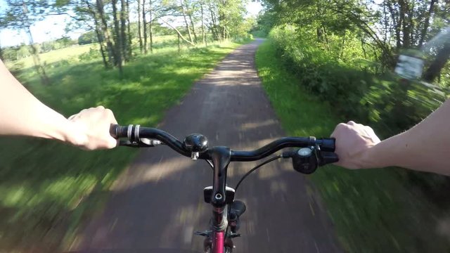 Riding bike on rural road in sunshine. Summer leisure activity in pov perspective. 