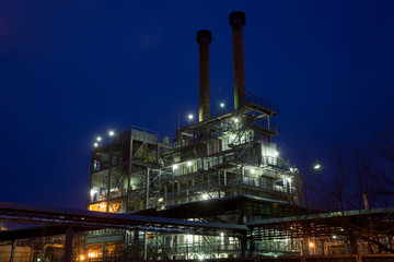 building with two tall pipes at  chemical plant at night on  background of  dark sky