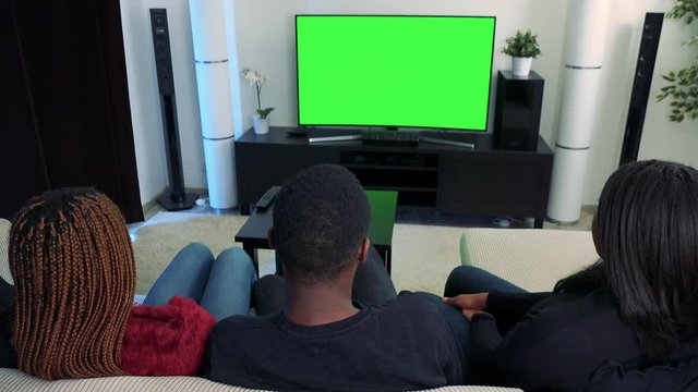 Three african friends watch television in living room and then they disagree